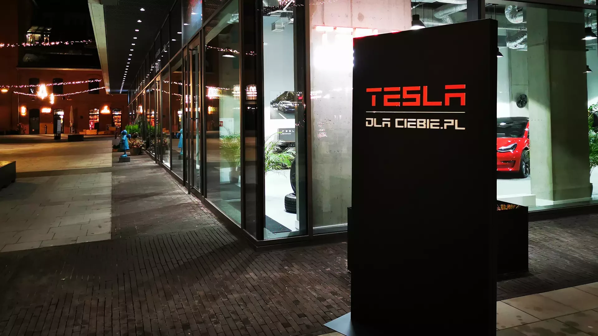 Pylon reklamowy 'Tesla dla Ciebie', zlokalizowany przy wejściu do salonu Tesla w Centrum Praskim Koneser w Warszawie, prezentujący nowoczesne pojazdy elektryczne